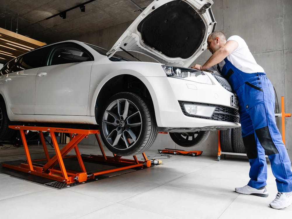 Oto servis lift üzerinde beyaz araç bakımı